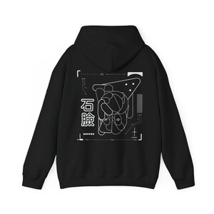 May include: Black hooded sweatshirt with a white graphic design on the back. The design features a geometric pattern with a hand and the Japanese characters "石鹸" (meaning "soap").