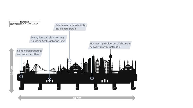 May include: Black metal wall-mounted key holder featuring a skyline silhouette with hooks. The key holder is 12 cm high and 30 cm wide. The design includes architectural details and the text "metallmanufaktur".