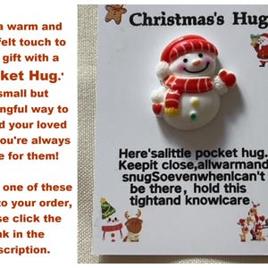 Peut inclure: Un bonhomme de neige blanc avec un chapeau et une &eacute;charpe rouges, tenant un c&oelig;ur rouge. Le texte dit "Christmas's Hug. Here's a little pocket hug. Keep it close, all warm and snug. So even when I can't be there, hold this tight and know I care."