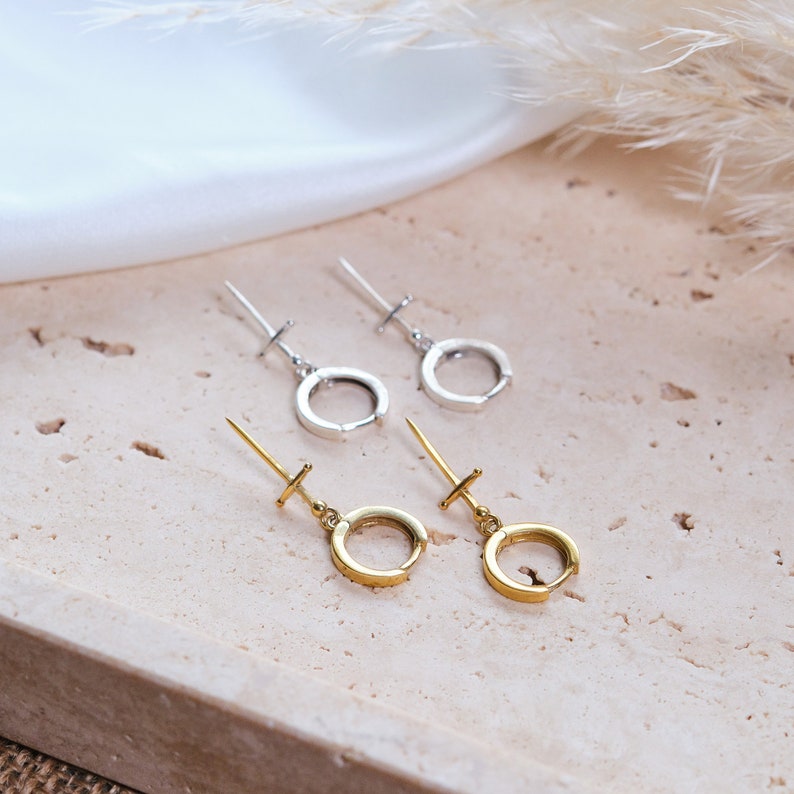 Peut inclure: Deux paires de boucles d'oreilles cr&eacute;oles, une paire est argent&eacute;e et l'autre dor&eacute;e. Les boucles d'oreilles sont sur une surface textur&eacute;e brun clair.