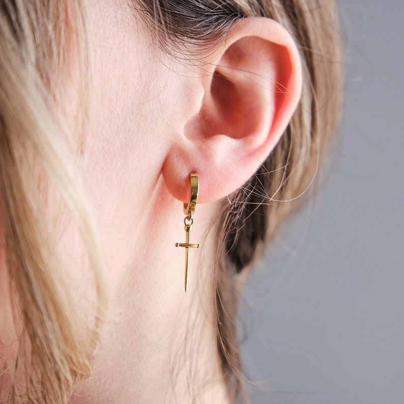 Peut inclure: Boucle d'oreille en or avec un pendentif en forme de croix.