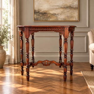May include: A rectangular wooden console table with a rich dark brown finish. The table features four turned legs with decorative carved details, a scalloped apron with a circular relief pattern, and a central cross-stretcher connecting the legs.