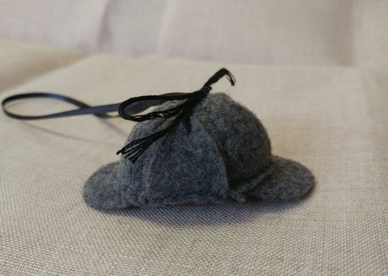 Pode incluir: Um chap&eacute;u de feltro cinza com uma fita preta e um cord&atilde;o preto.