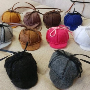 Pode incluir: Conjunto de chap&eacute;us de feltro em v&aacute;rias cores, incluindo cinza, marrom, preto, branco, azul, rosa e amarelo. Cada chap&eacute;u tem um pequeno la&ccedil;o e uma aba.