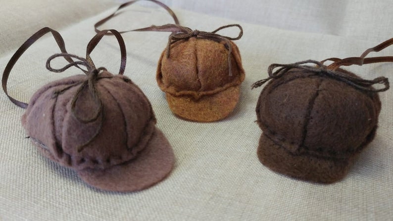 Pode incluir: Tr&ecirc;s chap&eacute;us de feltro em cores castanho e bege. Cada chap&eacute;u tem uma aba e um la&ccedil;o no topo. Os chap&eacute;us est&atilde;o pendurados numa corda.