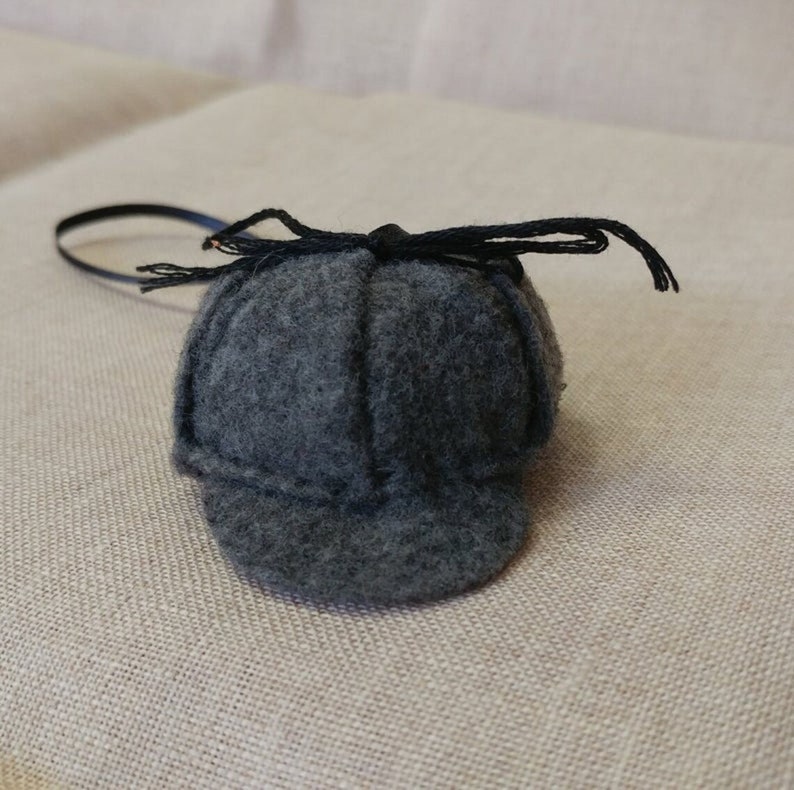 Pode incluir: Um chap&eacute;u de feltro cinza estilo Sherlock Holmes com uma fita preta e uma aba preta.