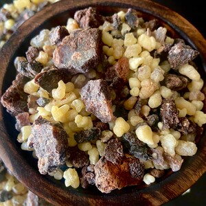 Puede incluir: Un cuenco de madera lleno de una mezcla de trozos de resina marr&oacute;n, negro y amarillo. La resina se utiliza para incienso y aromaterapia.