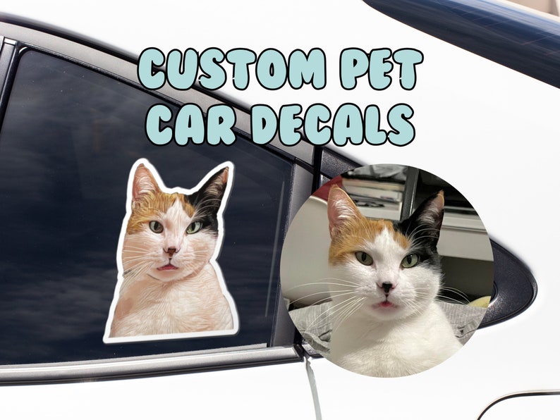 May include: Custom pet car decals featuring a white, black, and orange cat with green eyes. The cat is looking directly at the camera with its tongue sticking out. The text "CUSTOM PET CAR DECALS" is written in blue letters on a white background.