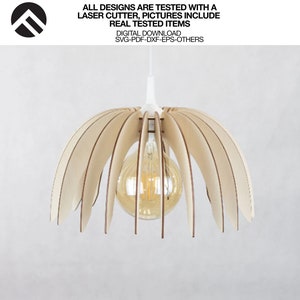 May include: A wooden pendant light fixture with a light bulb inside. The light fixture is made of thin, curved pieces of wood that resemble petals. The light fixture is hanging from a white cord.