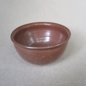 May include: A small, round, brown ceramic bowl with a slightly textured surface.