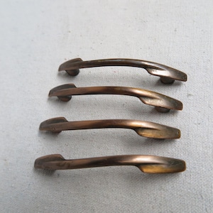 May include: Four antique bronze cabinet door pulls with a curved design.