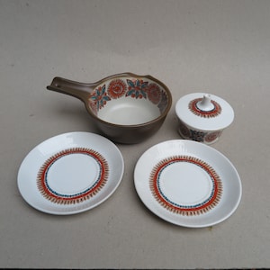 May include: A set of vintage brown and white ceramic dishes with a floral pattern. The set includes a small bowl with a handle, a lidded sugar bowl, and two saucers.