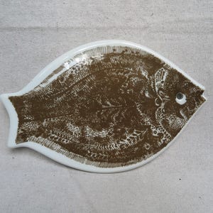 May include: A set of three ceramic mugs with a speckled, matte finish. The mugs are in shades of cream, light gray, and dark gray. Each mug has a simple, minimalist design and a rounded handle.