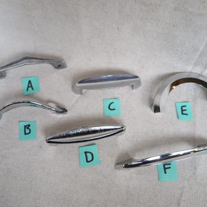May include: A collection of six chrome cabinet or drawer pulls in various designs. The pulls are labeled A through F with different shapes, including curved, arched, and straight styles. The pulls are made of shiny metal.
