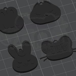 May include: Four black charm pendants in animal shapes: a frog, a cat, a bunny, and a mouse. The mouse pendant has the text "makes things". Each charm has a small hole for hanging.