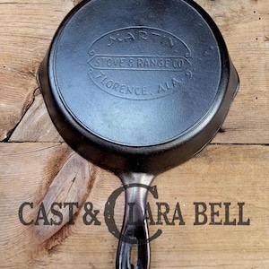 May include: Black cast iron skillet with a handle. The skillet has the words "Martin Stove & Range Co. Florence, Ala." embossed on the bottom.