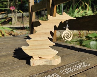 May include: Wooden Christmas tree ornament holder with a spiral ornament earring hanging from it. The tree is on a wooden surface with the words "Merry Christmas" written on it.