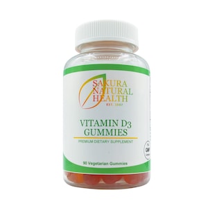 May include: A clear plastic bottle of Sakura Natural Health Vitamin D3 Gummies. The label features green and white text with the brand name and product information. The bottle contains 90 vegetarian gummies, visible at the bottom.