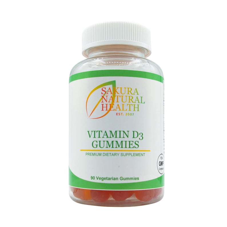 May include: A clear plastic bottle of Sakura Natural Health Vitamin D3 Gummies. The label features green and white text with the brand name and product information. The bottle contains 90 vegetarian gummies, visible at the bottom.