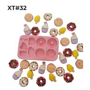 May include: A rectangular pink silicone mold with eight assorted cavities, surrounded by miniature resin charms shaped like donuts, cupcakes, cookies, and popsicles in pastel colors. The text XT#32 is printed in black in the upper left corner.