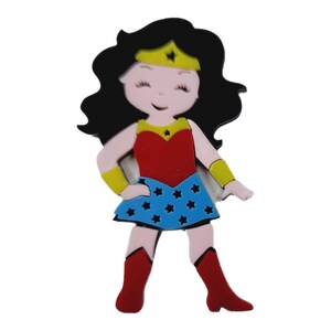 May include: A cartoon-style Wonder Woman figure with black hair, a yellow tiara, and a red and blue outfit. The figure is smiling and has a blue skirt with white stars, red boots, and yellow wrist cuffs.