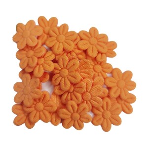 May include: A group of ten orange fabric flower embellishments. The flowers are all the same size and shape, with five petals each. They are arranged in a loose pile, with some of the flowers overlapping.
