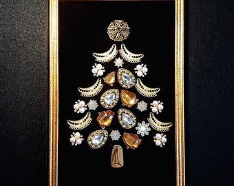 May include: A gold framed picture with a black background featuring a Christmas tree made of gold and clear rhinestones and other decorative embellishments.