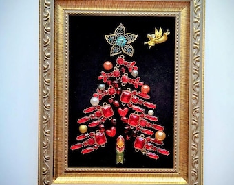May include: A framed Christmas tree made of red and gold jewels, beads, and a blue star on a black velvet background.