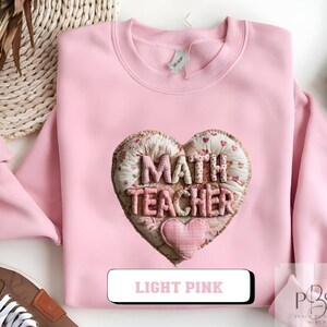May include: Light pink sweatshirt with a heart-shaped patch that reads "MATH TEACHER". The patch is made of fabric with a floral pattern and a smaller pink heart. The text "LIGHT PINK" is displayed in a white rectangle.