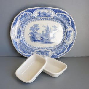 May include: A blue and white oval serving platter with a blue and white floral design. Two small white rectangular dishes are in the foreground.