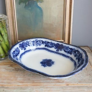 May include: An oval ceramic serving dish featuring a white base with a deep blue floral transferware pattern along the scalloped rim and a matching blue floral motif centered at the bottom of the basin, showcasing a classic decorative design.