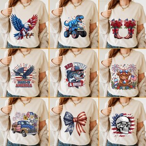 May include: Collection of beige t-shirts with patriotic designs. Graphics include an eagle, a dinosaur on a truck, cowboy boots, an American flag, a fish, a cow, a truck, a bow, and a skull, all in red, white, and blue.