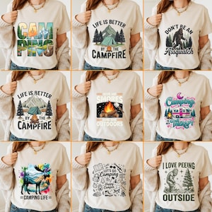 Puede incluir: Una colección de camisetas beige con gráficos temáticos de camping. Los diseños incluyen textos como "Camping", "Life is Better by the Campfire" y "Camping is My Therapy". Otros diseños presentan un Bigfoot, una fogata y un alce.