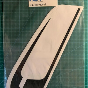 May include: A white sticker with a black outline in the shape of a stylized letter "C". The sticker is labeled "HV00 241" and "HONDA VINTAGE TEAM CB 250/360 6".