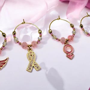 Hübsche Awareness-Drink-Marker, Flügel, Band, weibliches Zeichen und rosa Band-Charms, rosa facettierte Perlen und vergoldete Halter