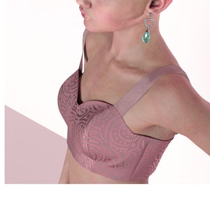Może przedstawiać: Różowy, wzorzysty top w stylu crop top z cienkimi ramiączkami. Top ma dekolt w kształcie serca i ozdobny wzór.