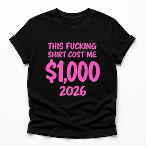 May include: Black t-shirt with the text "THIS FUCKING SHIRT COST ME $1,000 2026" in pink. The shirt has short sleeves and a crew neck.