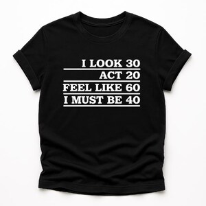 Może przedstawiać: Czarny t-shirt z białym napisem: "I LOOK 30, ACT 20, FEEL LIKE 60, I MUST BE 40". Koszulka ma krótkie rękawy i okrągły dekolt. Tekst jest wyśrodkowany na przodzie koszulki.