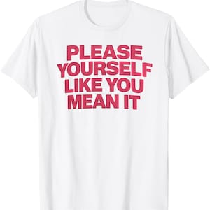 May include: White t-shirt with the phrase "PLEASE YOURSELF LIKE YOU MEAN IT" printed in bold, red letters. The shirt is a classic crew neck style.