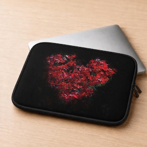May include: A black laptop sleeve featuring a vibrant, heart-shaped cluster of bright red Japanese maple leaves centered on the front. The sleeve has a zippered closure and is shown with a silver laptop partially inserted into the main compartment.