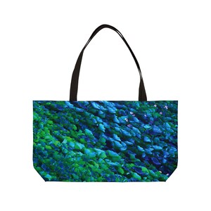 May include: A tote bag with a vibrant, abstract design of blue and green leaves. The bag has a black handle and a rectangular shape, perfect for carrying items. The design is reminiscent of a lush, natural landscape.
