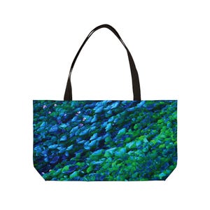 May include: A tote bag featuring a vibrant, close-up image of lush green and blue foliage. The bag has a black handle and a rectangular shape, perfect for carrying items.
