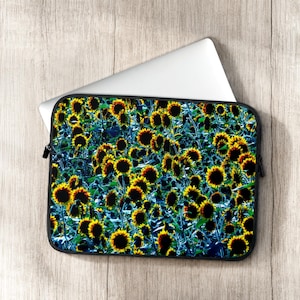 May include: A rectangular laptop sleeve featuring a dense, repeating pattern of yellow sunflowers with dark brown centers against a deep blue and black background, partially covering a silver laptop with a smooth, metallic finish.
