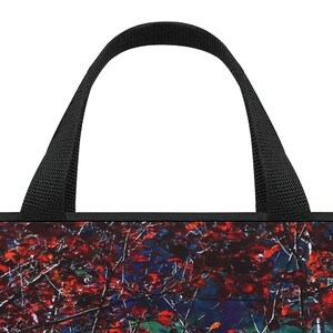 Puede incluir: Un bolso tote con asa negra y un dise&ntilde;o vibrante y colorido. El patr&oacute;n del bolso presenta un primer plano de hojas y ramas rojas sobre un fondo azul oscuro y verde. El asa est&aacute; hecha de un material tejido resistente.
