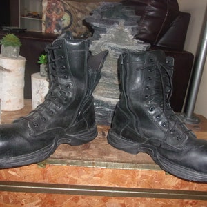May include: A pair of black leather work boots with a zipper on the side and laces up the front. The boots have a thick, rugged sole.