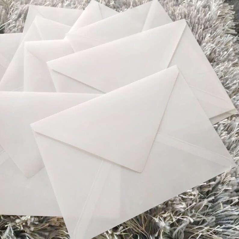May include: A stack of white envelopes, with the top envelope folded open to reveal the inside.