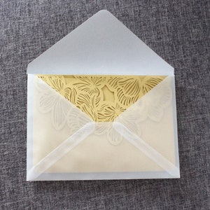 May include: A white envelope with a gold, laser-cut floral design on the inside.