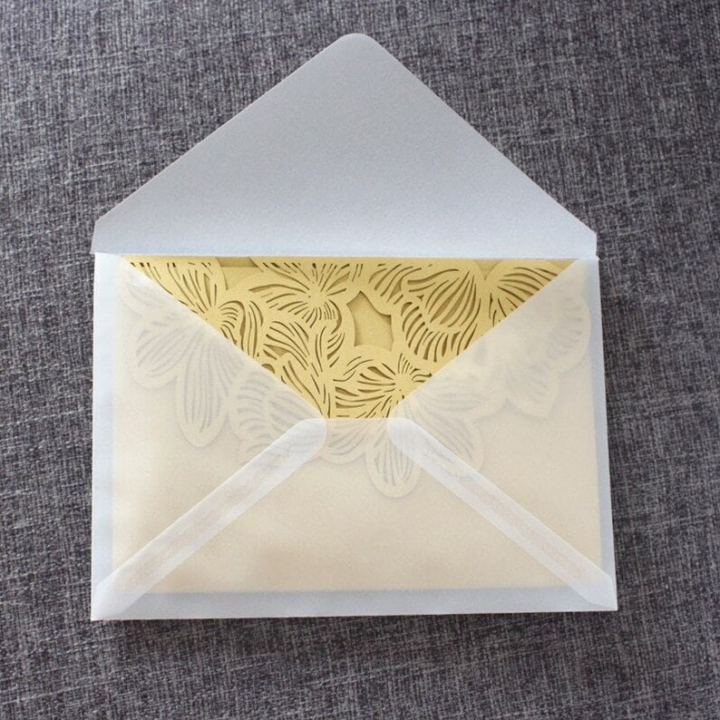 May include: A white envelope with a gold, laser-cut floral design on the inside.