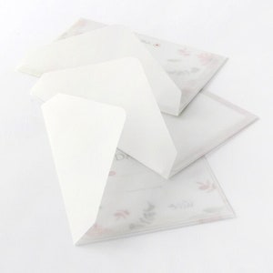 May include: Three white envelopes with a floral pattern on the bottom envelope. The top envelope is folded over the middle envelope.