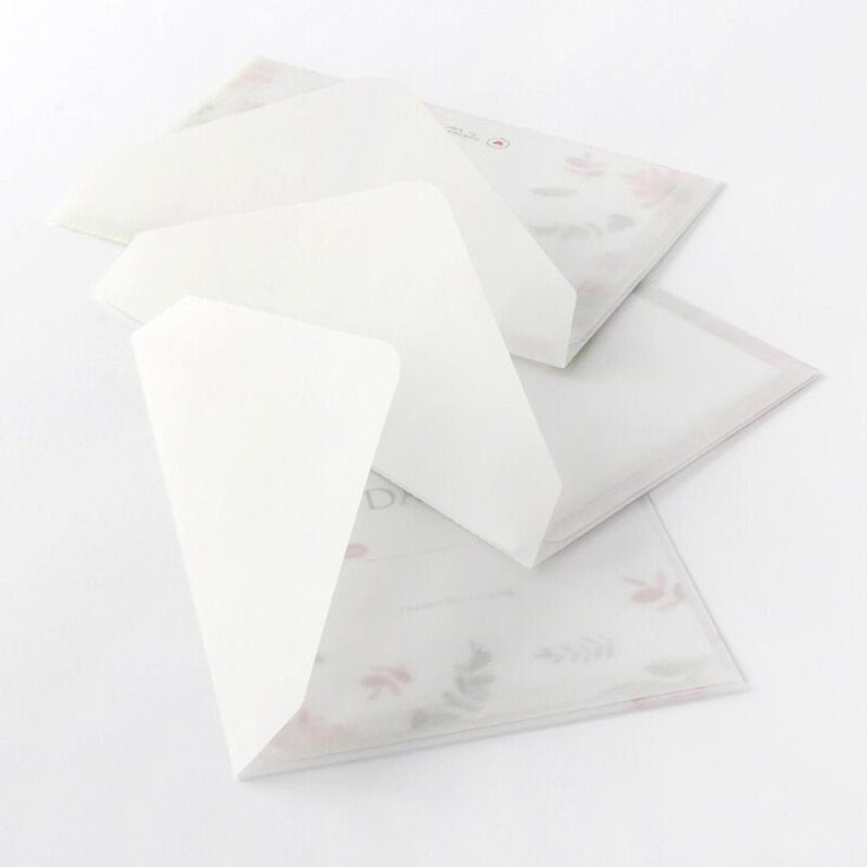 May include: Three white envelopes with a floral pattern on the bottom envelope. The top envelope is folded over the middle envelope.